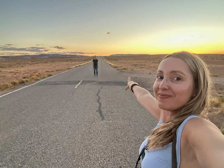Andrea pointing towards Felix and a sunset on County Road 443 in Utah west of Four Corners.