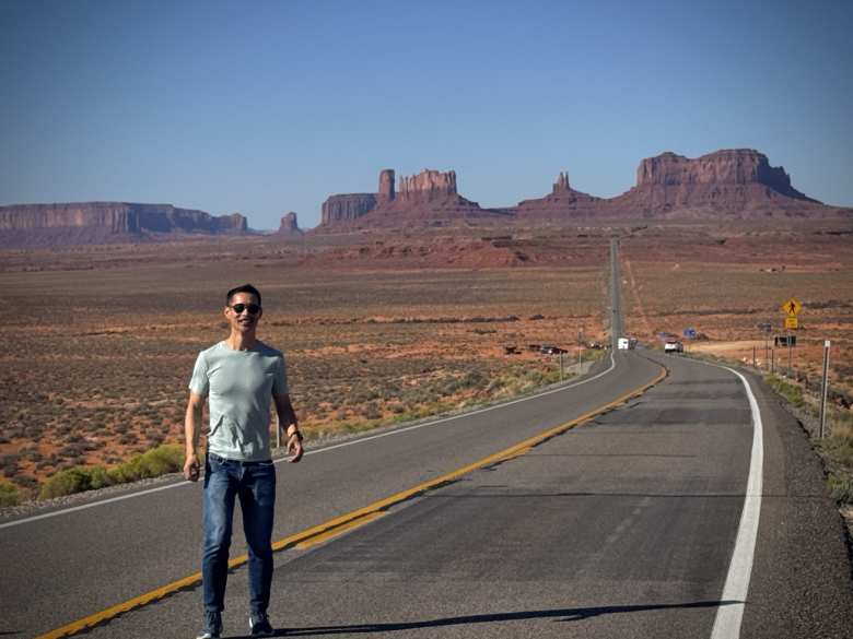 Felix standing on Highway 163 at Forest Gump Hill, with the view of Monument Valley made famous by the film Forest Gump.