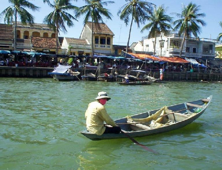 Man in canoe at harbor in Hoi An.