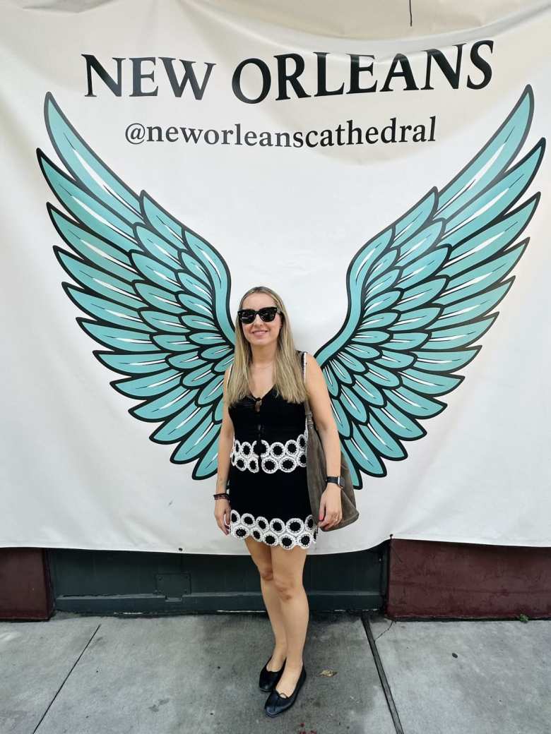 Andrea in front of a banner with wings at the New Orleans Cathedral.