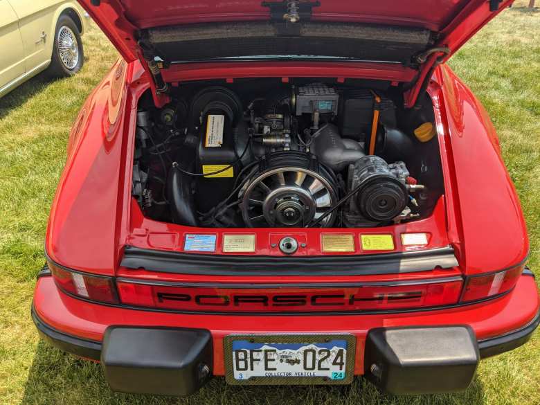 The engine bay of a red air-cooled Porsche 911.