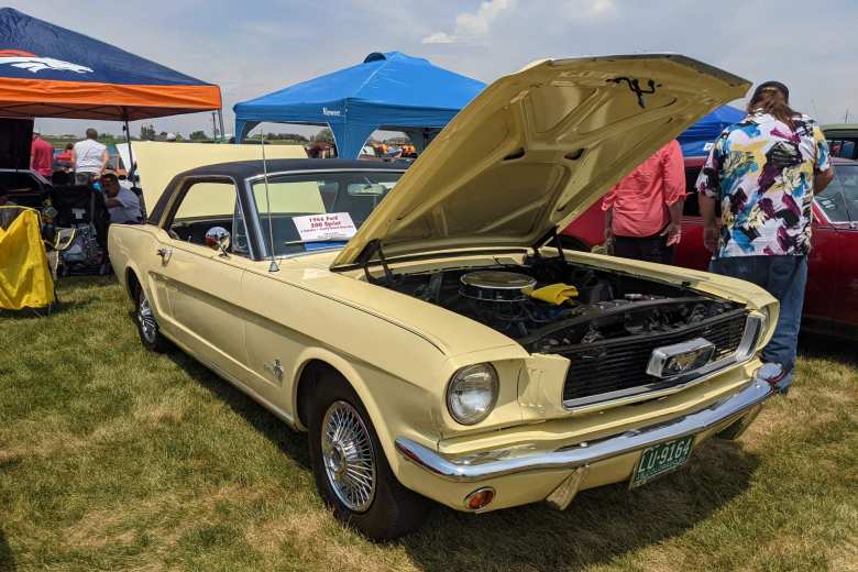 A yellow 1965 Ford Mustang with black vinyl roof.