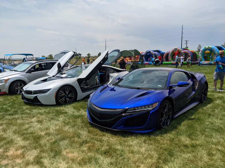 A blue Acura NSX (circa 2020) with a white BMW i8 and a silver Dodge Caliber.