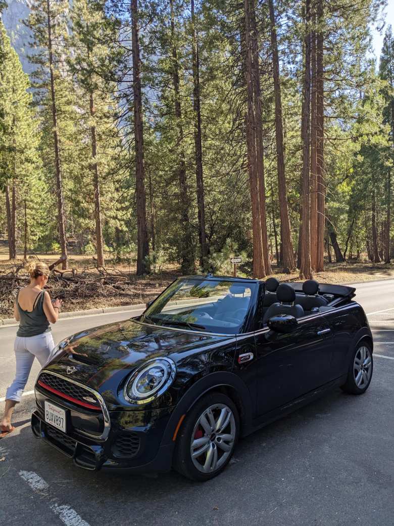 Andrea walks by our black 2021 MINI John Cooper Works Convertible rental car in Yosemite.