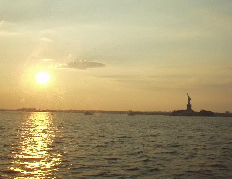 The view of the Statue of Liberty from the ferry, as lit by a dawning sun.