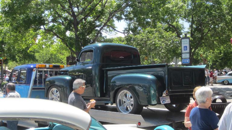 green vintage Ford pickup truck on tow truck bed