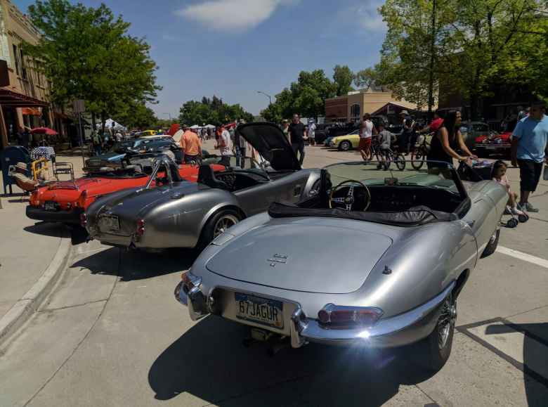 An orange-red MGB, silver AC Cobra (probably a replica), and and silver Jaguar E-Type convertible.