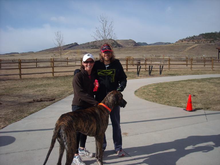 Great Dane with orange collar, Katie Quatrano wearing white cap, Nick Clark wearing red cap