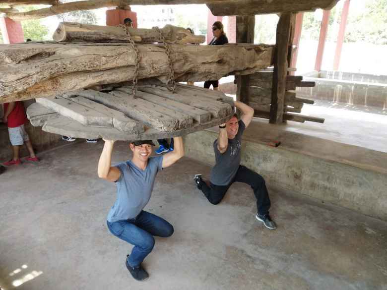 Felix and Matthew looking like they are holding up the top of a pisco barrel.