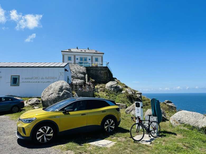 A yellow Volkswagen ID.4 electric car and my black Litespeed carbon fiber bicycle by a charger at the Semaforo de Fisterra. 