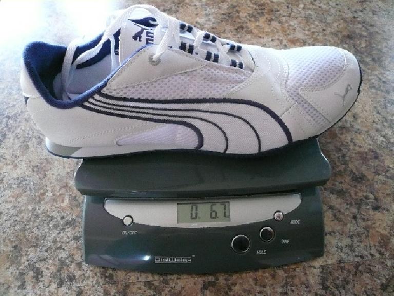 a white Puma Saloh shoe on a postal scale registering 6.7 ounces