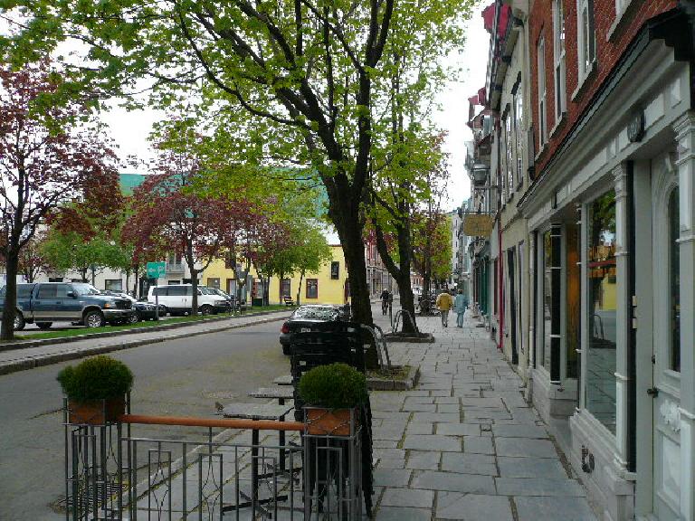 Sidewalk paved with rectangular pavers along storefronts in Quebec City.