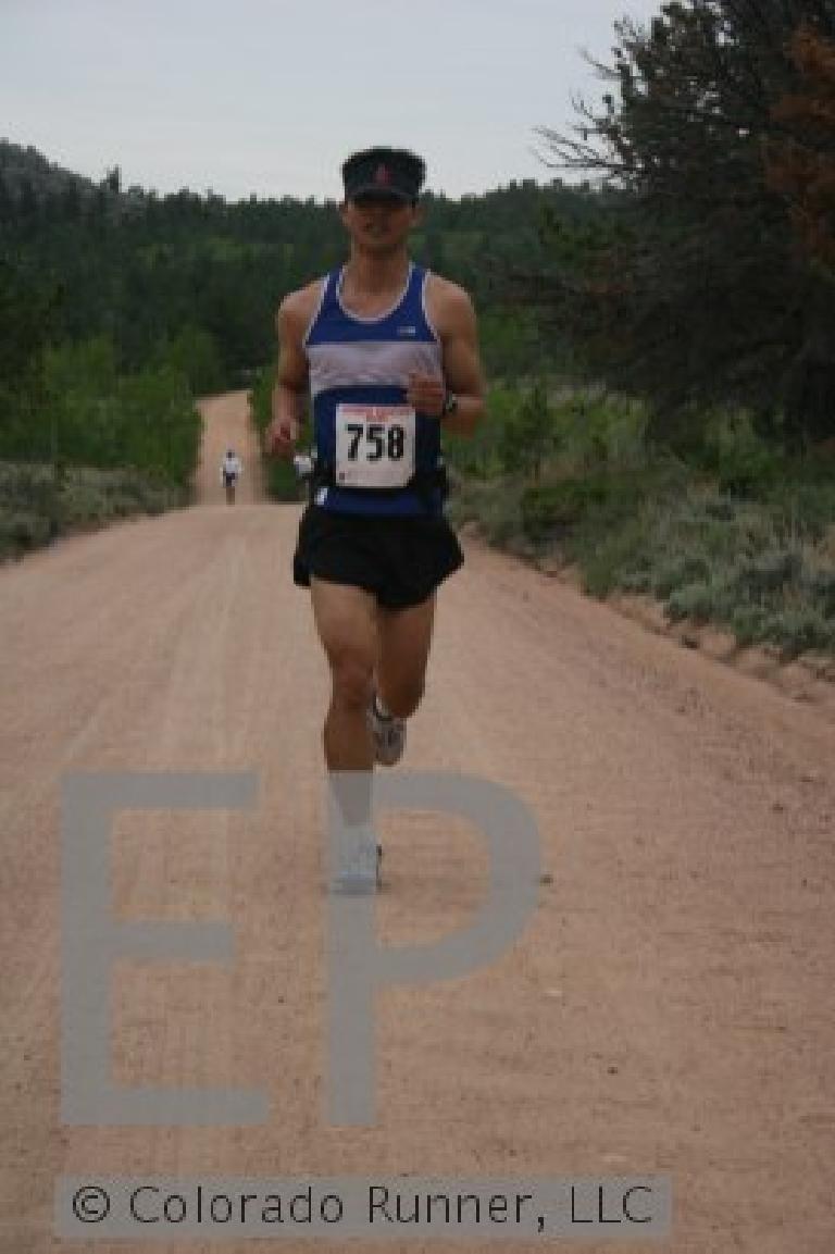 Felix Wong wearing a blue and white singlet and number 758 running on a dirt trail in the 2006 Rocky Mountain Double Marathon
