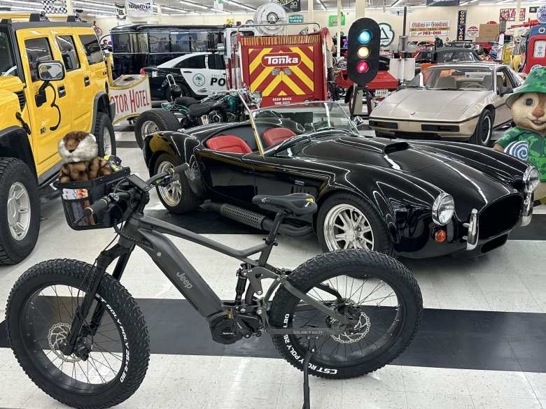 A 2022 Jeep e-bike that was unveiled on Super Bowl Sunday/Groundhog Day. Because of the coincidence, Jeep enlisted Bill Murray to help promote it. In the background is a black Shelby Cobra (most likely a replica) and a 1986 Pontiac Fiero used in Breaking Bad. A 2022 Jeep e-bike that was unveiled on Super Bowl Sunday/Groundhog Day. Because of the coincidence, Jeep enlisted Bill Murray to help promote it. In the background is a black Shelby Cobra (most likely a replica) and a 1986 Pontiac Fiero used in Breaking Bad.
