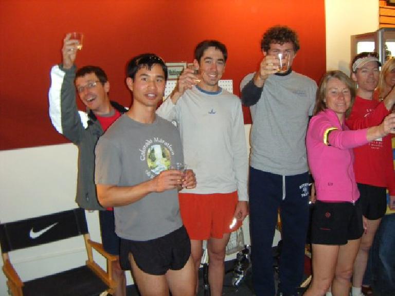 Scott Slusher, Felix Wong, man in white shirt, Tim Vail, Catherine Speights, Dan Jones holding up plastic cups for a cheers in the new Runners Roost