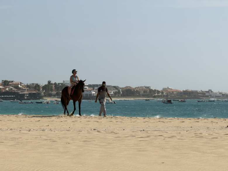A woman riding a horse on Santa Maria beach.