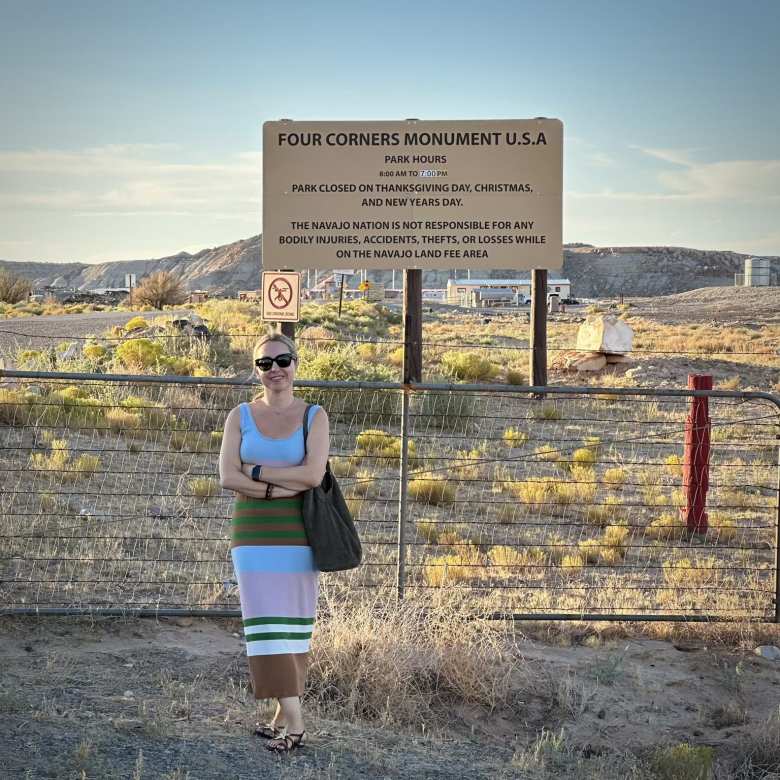 Andrea in front of the Four Corners Monument sign.