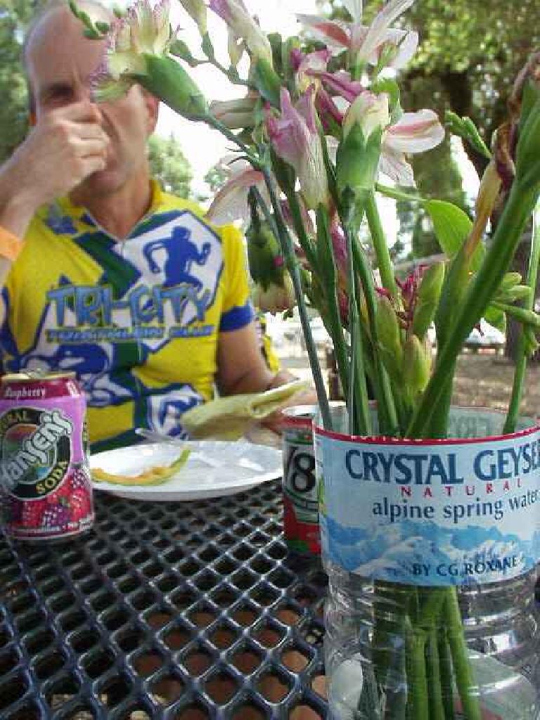 [Mile 65, 1:50 p.m.] At lunch the Santa Cruz Cyclists had great food waiting for us; a lady singing and playing the guitar; and even had flowers set on the outdoor tables for us.  In the background is Steve munching on a yummy potato.