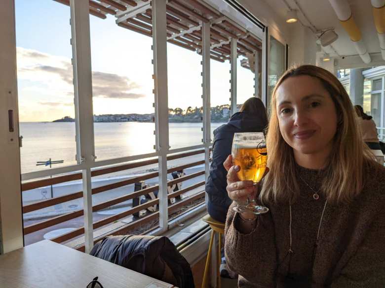 Andrea with a caña at a bar overlooking a beach in Sanxenxo.