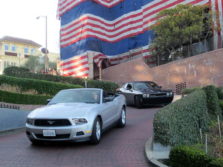 All-American scene: Kelly in a Ford Mustang being followed by a Dodge Challenger with the U.S. colors in the background on Lombard St.