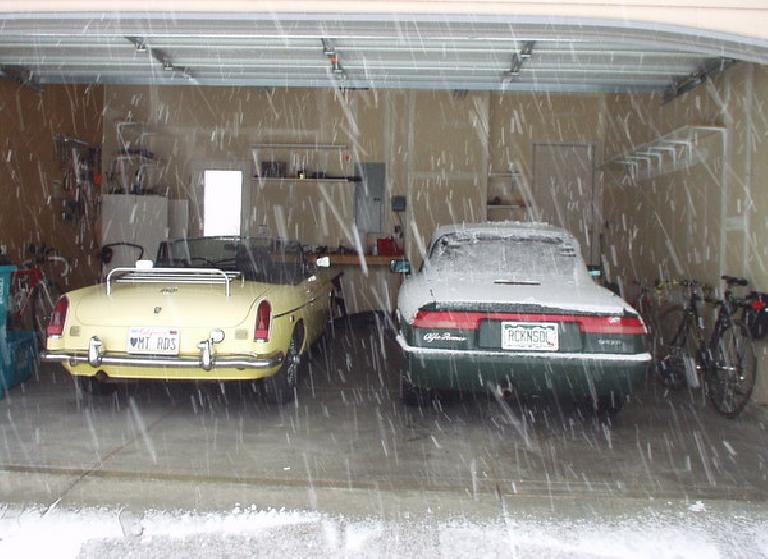 snow falling outside garage containing yellow 1969 MGB roadster and snow-covered green 1991 Alfa Romeo Spider Veloce