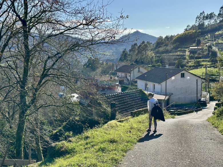 Andrea peering over the side of a narrow road near some residences in Soutomaior.