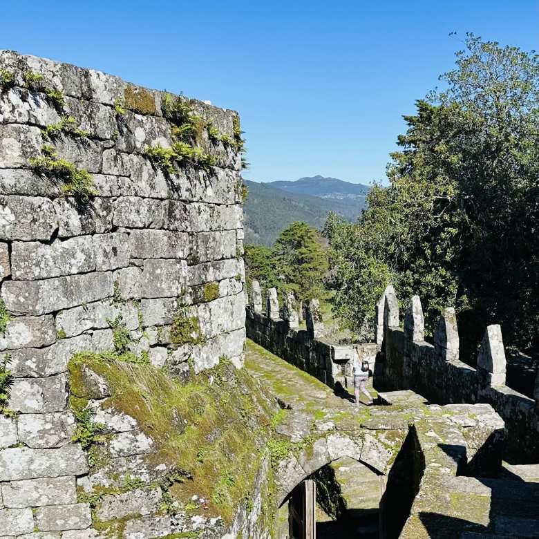 Andrea strolling along the wall walk beside the battlements of the Castle of Soutomaior.