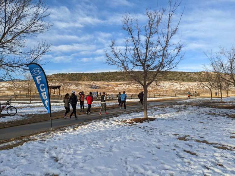 Wave 18 runners pass by Fort Collins Running Club (FCRC) banner in the Spring Canyon Park 5k Tortoise & Hare race.