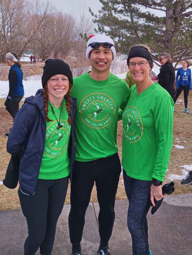 Brooke, Felix, and Cathy wearing green Sweaty Sweater 4 Mile shirts from the race they ran the day before.