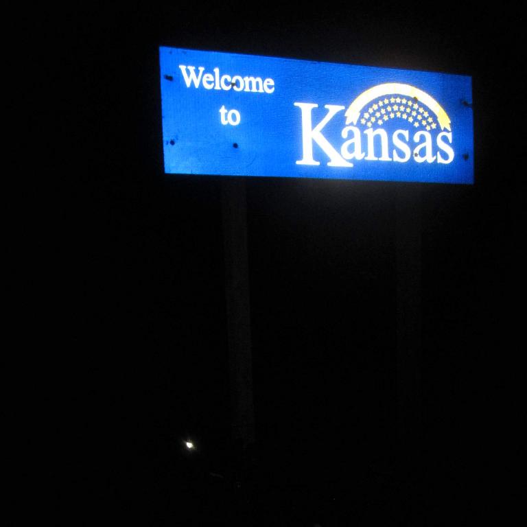 blue Welcome to Kansas sign, night