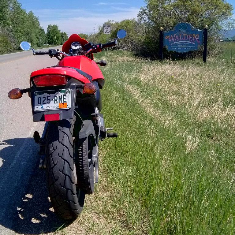 Felix Wong's red 2003 Buell Blast in front of a sign in Walden, Colorado.