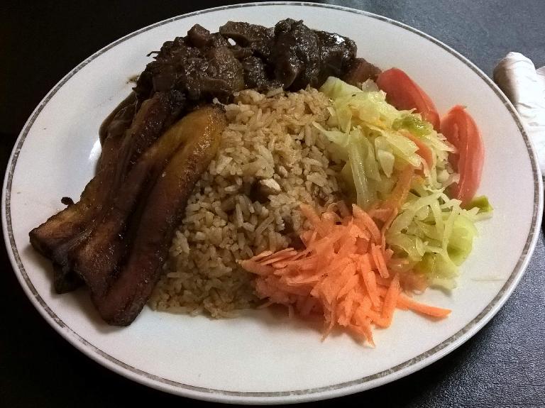 An entrée of oxtail, brown rice, carrots and cabbage at Nicolette's Caribbean Café in Tampa, Florida.
