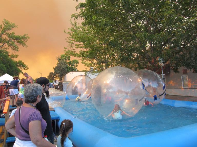 Kids in air bubbles in a giant pool.  Note the orange sky due to smoke from the High Park Fire.