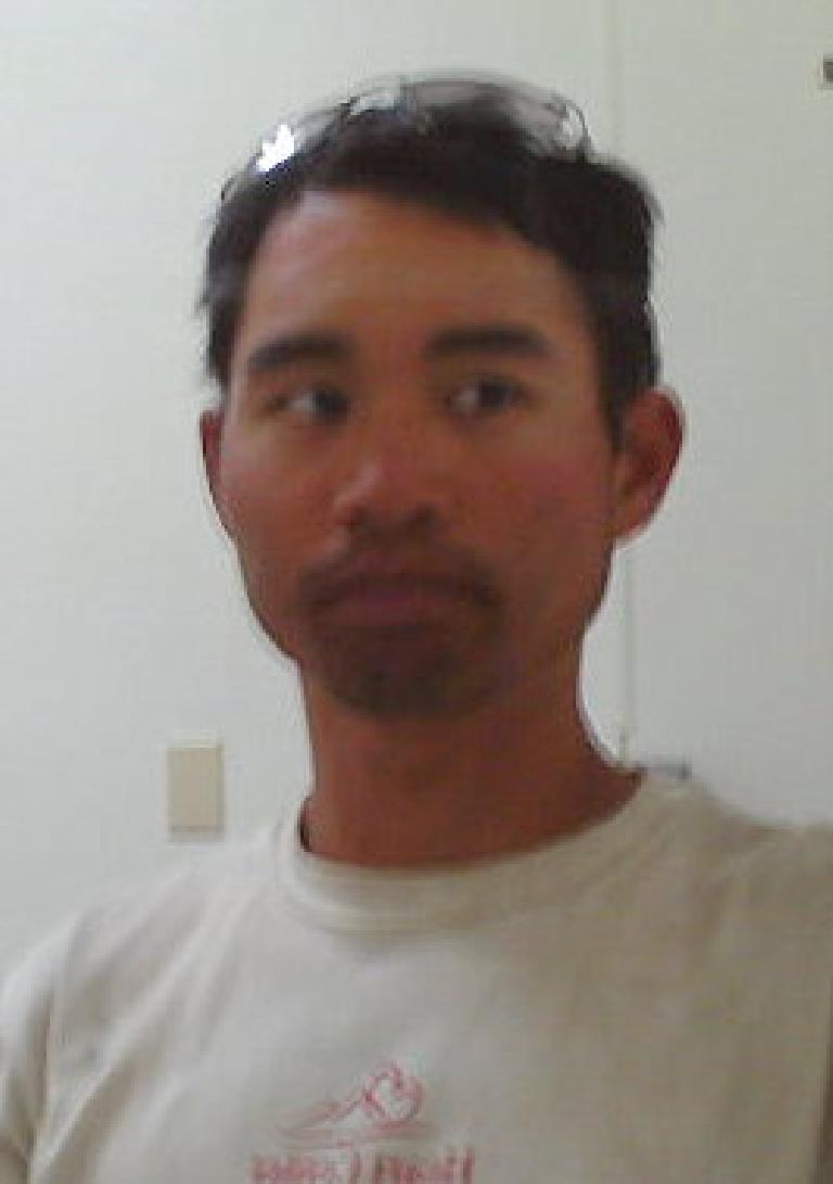 Felix Wong wearing white Heart Center of the Rockies shirt, looking unshaven with glasses on top of head