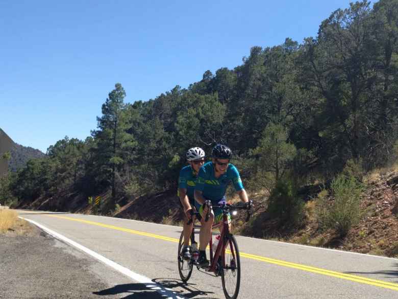 Chris Scott and Dan Berlin cruising on a pine tree-lined road in southern Colorado.