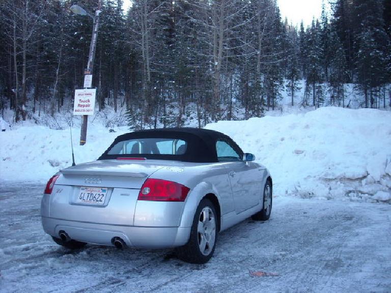right rear view of silver 2001 Audi TT Roadster Quattro, with top up on snow-covered parking lot in front of snow-covered field with trees