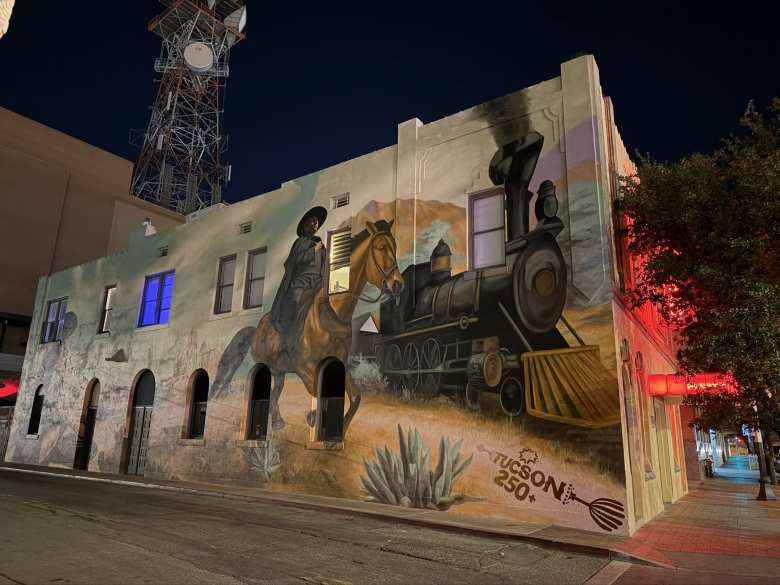 Mural of a horseman riding next to a train in downtown Tucson, Arizona.