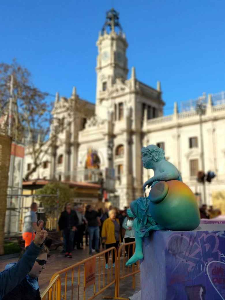 A smaller green ninot (a caricature of something usually made of paper and wax) with Valencia's City Hall in the background.