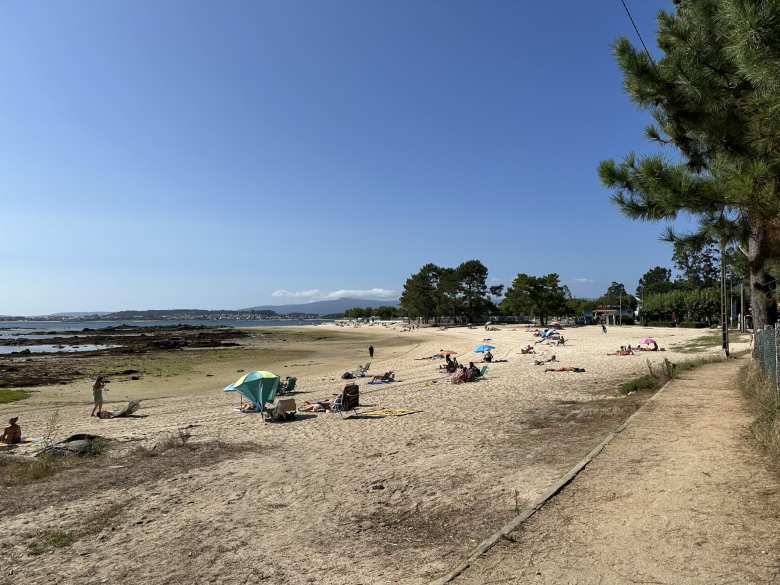 People relaxing in the afternoon sun at a beach in Vilanova de Arousa.