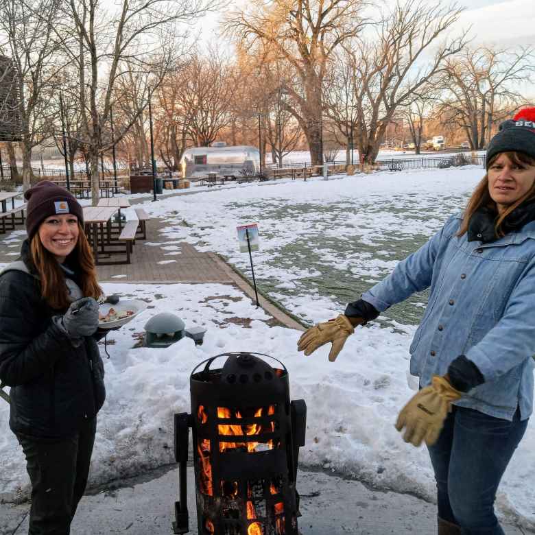 Brooke and an unknown woman warming up by the fire at New Belgium Brewing for Winter Bike to Work Day.