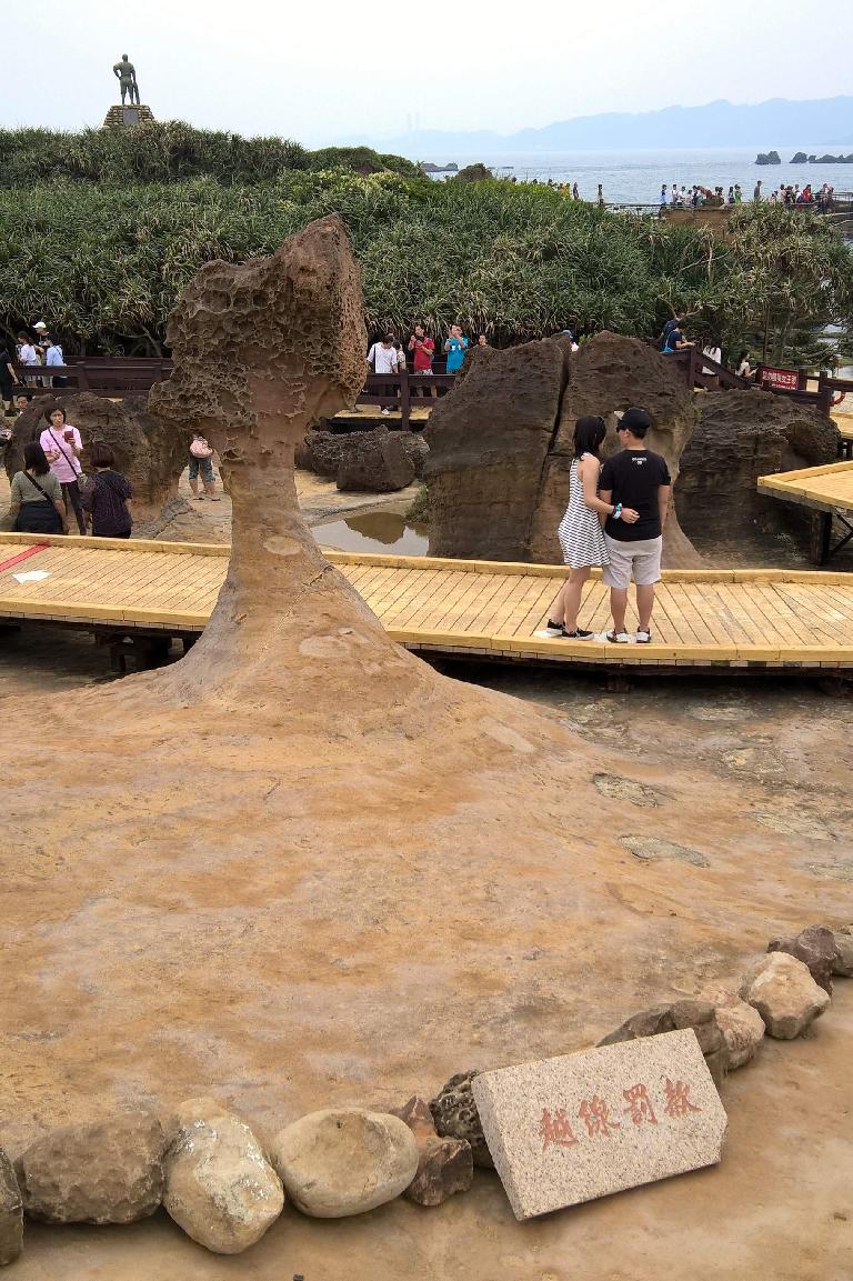 A couple posing by the Queen's Head in Yehliu Geopark in New Taipei, Taiwan.