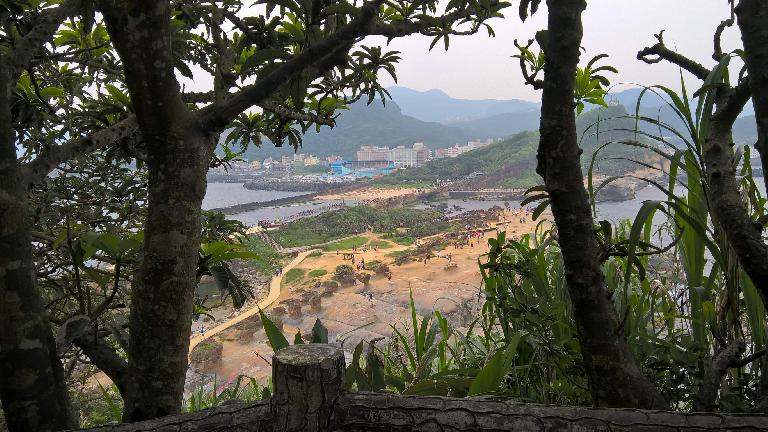 The view of buildings on the Yehliu Peninsula through trees at Yehliu Geopark.